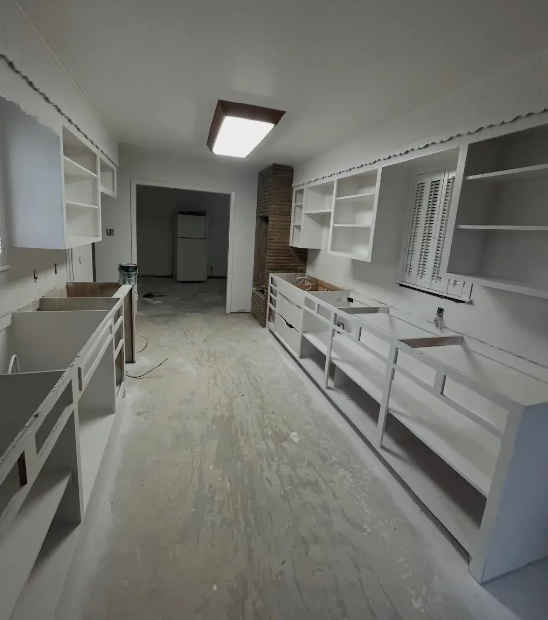 The same kitchen mid-remodel with cabinet frames stripped and the subfloor exposed